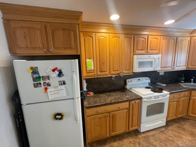 kitchen with decorative backsplash, white appliances, sink, and dark stone counters