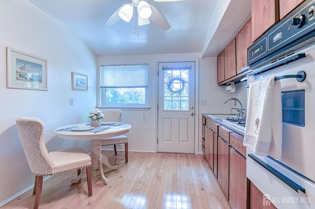 24 Grand Ave, South River, NJ 08882 - kitchen featuring brown cabinetry, white oven, a sink, and light wood-style flooring
