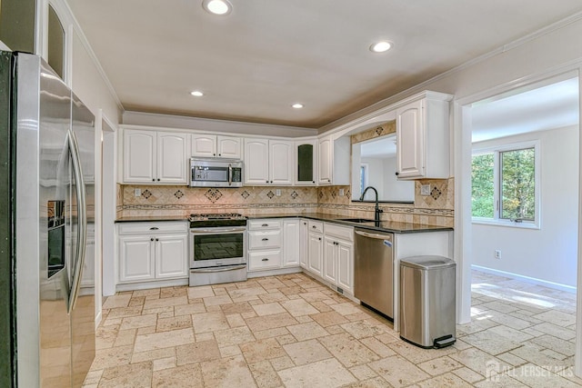 kitchen with sink, appliances with stainless steel finishes, ornamental molding, white cabinets, and decorative backsplash