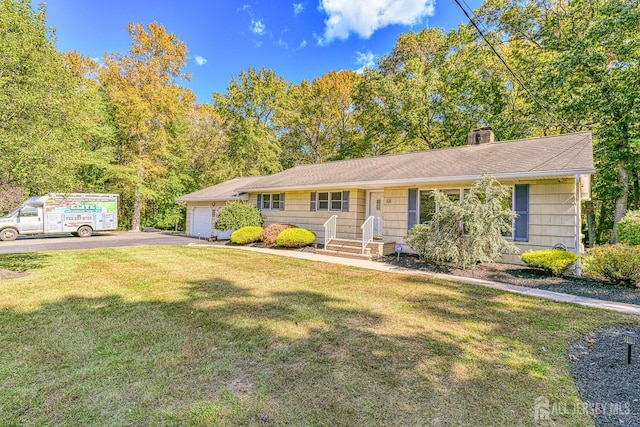 ranch-style home with a front yard, driveway, a chimney, and an attached garage