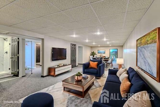 carpeted living room with a paneled ceiling