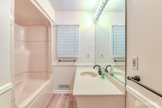 bathroom featuring wood finished floors, visible vents, vanity, and bathing tub / shower combination