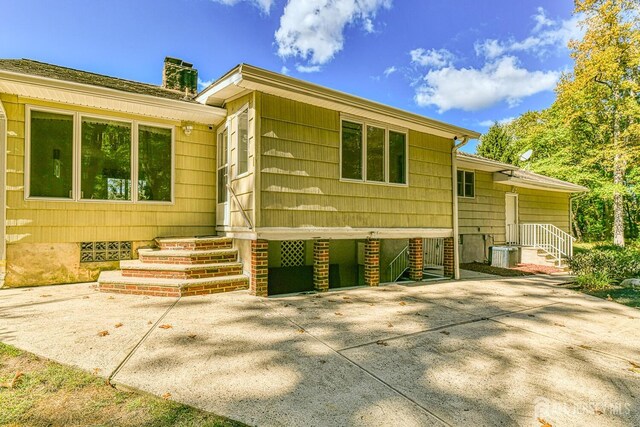 exterior space featuring entry steps, a chimney, and central AC unit