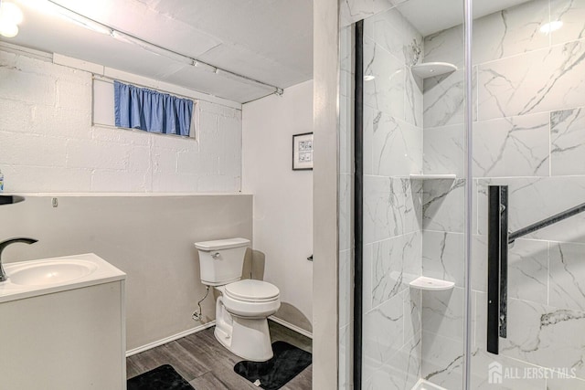 full bath featuring toilet, vanity, a marble finish shower, and wood finished floors