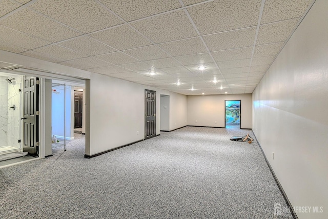 carpeted empty room featuring a paneled ceiling and baseboards