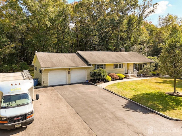 view of front of home with a garage, driveway, and a front lawn