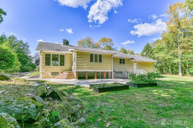 rear view of house with a garden, a chimney, and a lawn