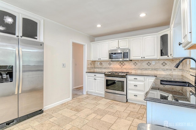 kitchen featuring stainless steel appliances, glass insert cabinets, stone tile flooring, and decorative backsplash