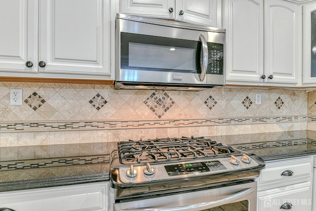 kitchen featuring appliances with stainless steel finishes, backsplash, glass insert cabinets, and white cabinets