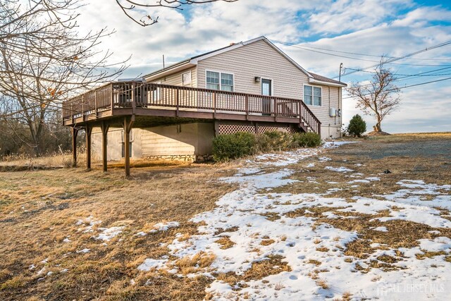 snow covered back of property with a wooden deck