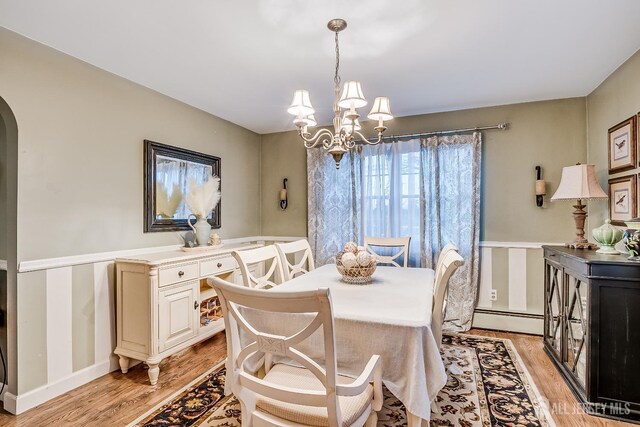 dining space featuring a baseboard heating unit, light hardwood / wood-style floors, and a notable chandelier