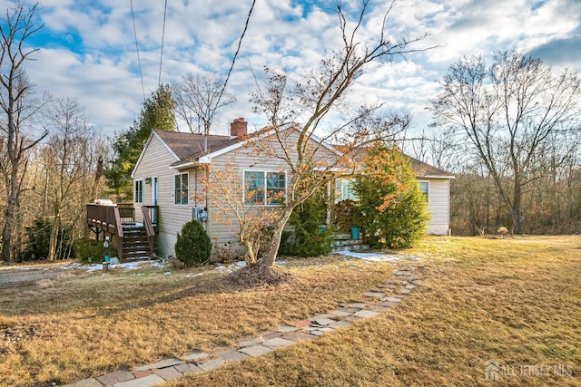 view of front facade featuring a wooden deck and a front yard