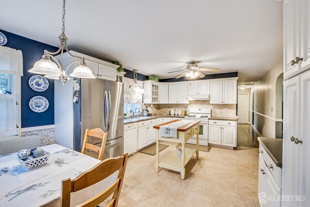 kitchen featuring white cabinets, wood counters, ceiling fan with notable chandelier, pendant lighting, and white range oven