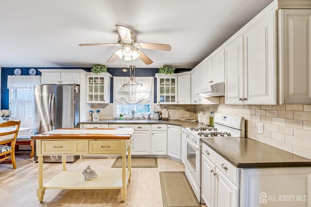 kitchen with white cabinets, ceiling fan, white range with gas stovetop, and plenty of natural light