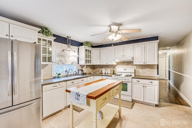 kitchen featuring white appliances, decorative light fixtures, tasteful backsplash, white cabinetry, and sink