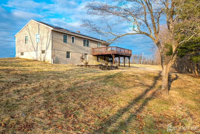 rear view of property featuring a lawn and a wooden deck