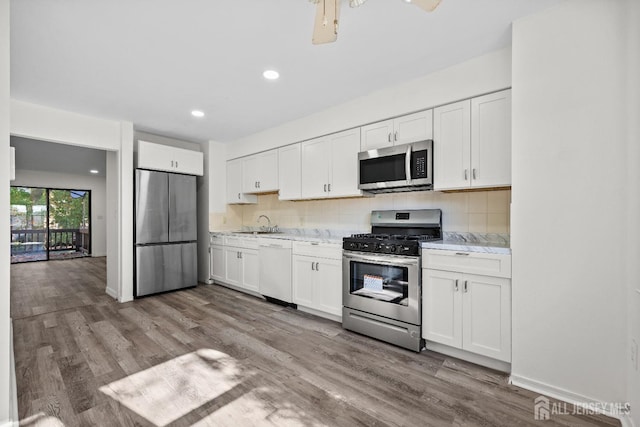 kitchen featuring stainless steel appliances, white cabinetry, and decorative backsplash