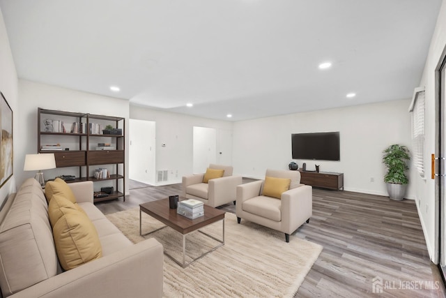 living room featuring baseboards, wood finished floors, and recessed lighting