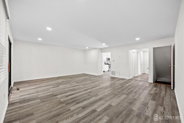 interior space featuring recessed lighting, baseboards, and wood finished floors