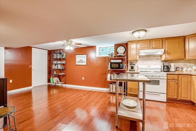 147 Smith St, South Plainfield, NJ 07080 - kitchen featuring white gas range oven, under cabinet range hood, baseboards, and light wood-style floors