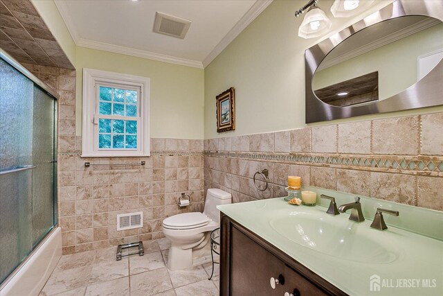 147 Smith St, South Plainfield, NJ 07080 - full bathroom featuring tile walls, toilet, ornamental molding, vanity, and bath / shower combo with glass door