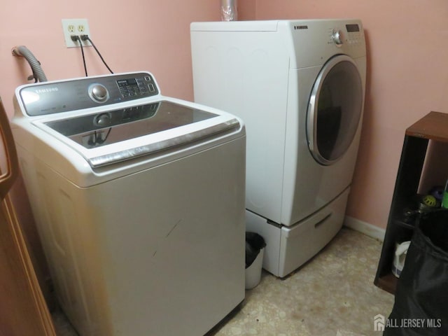 clothes washing area with separate washer and dryer and light flooring
