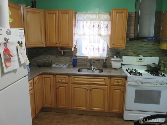 kitchen with white appliances, wall chimney range hood, a sink, tasteful backsplash, and wood finished floors