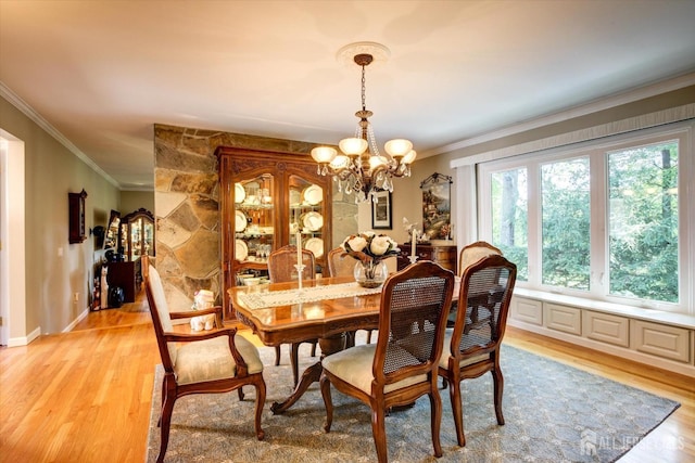 dining area with light wood-type flooring, an inviting chandelier, and ornamental molding