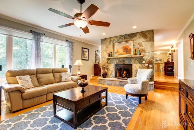 living room with baseboards, a stone fireplace, wood finished floors, and crown molding