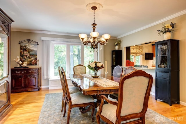 dining space featuring baseboards, a notable chandelier, ornamental molding, and light wood finished floors