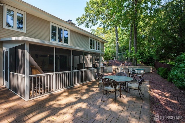 wooden terrace featuring outdoor dining area, a patio area, and a sunroom