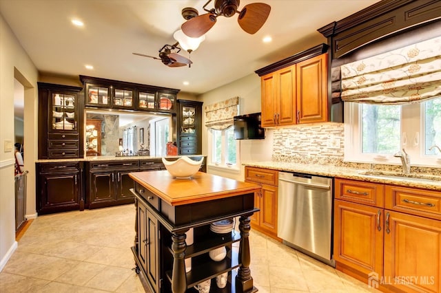 kitchen with stainless steel dishwasher, decorative backsplash, glass insert cabinets, and a sink