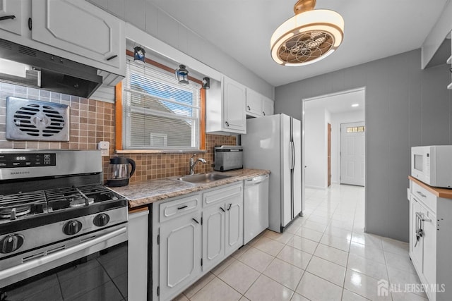 kitchen with decorative backsplash, exhaust hood, a sink, light countertops, and white appliances