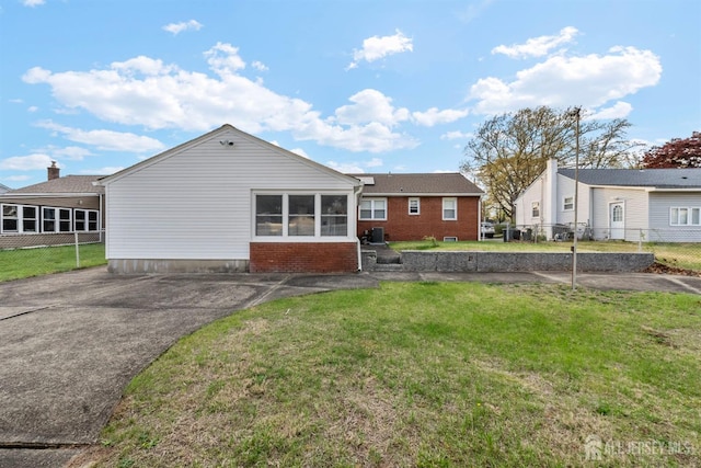 back of house featuring a yard, brick siding, and fence