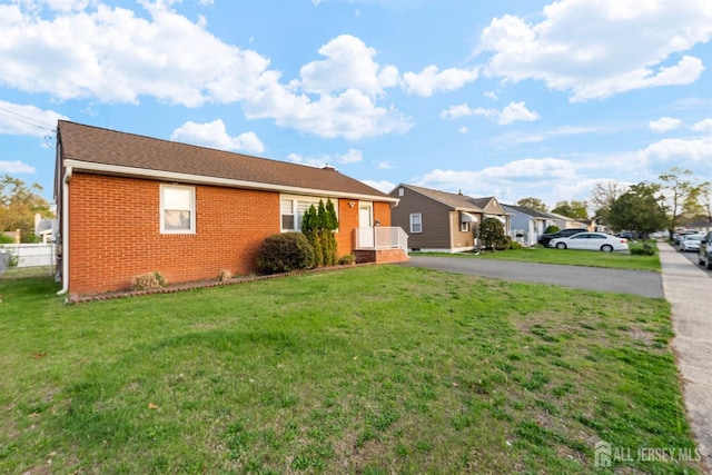 ranch-style home featuring aphalt driveway, a front lawn, and brick siding