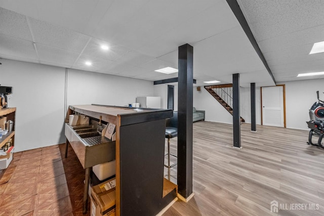 finished below grade area featuring stairway, recessed lighting, a drop ceiling, and light wood-type flooring