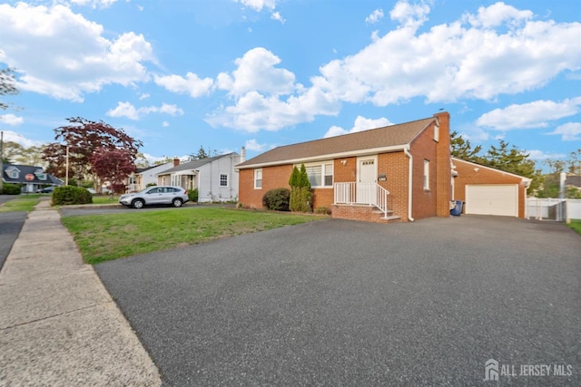 bungalow with a chimney, a garage, brick siding, aphalt driveway, and a front lawn