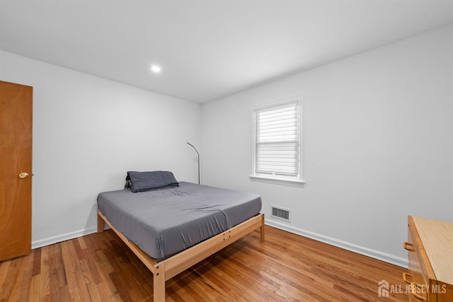bedroom featuring baseboards, wood finished floors, and visible vents