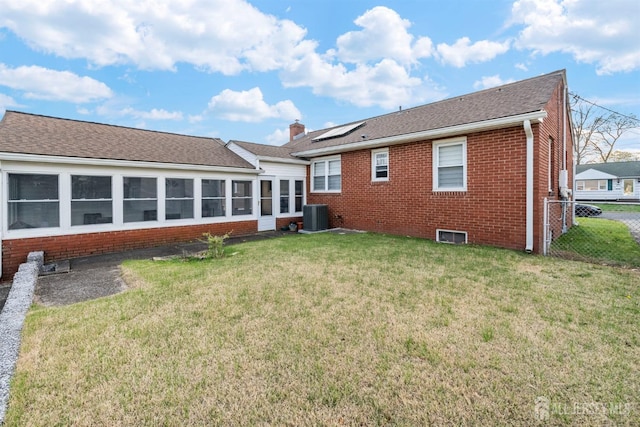 rear view of property with fence, a yard, central AC, and brick siding