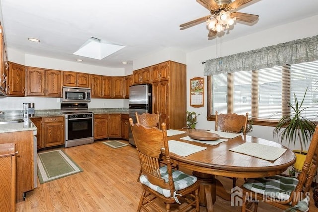 2338 Oxford Ave, South Plainfield, NJ 07080 - kitchen featuring appliances with stainless steel finishes, brown cabinets, a skylight, light wood-style flooring, and ceiling fan