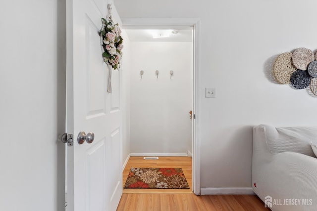 doorway with baseboards, visible vents, and wood finished floors