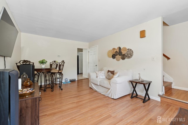living area featuring baseboards, stairs, and wood finished floors