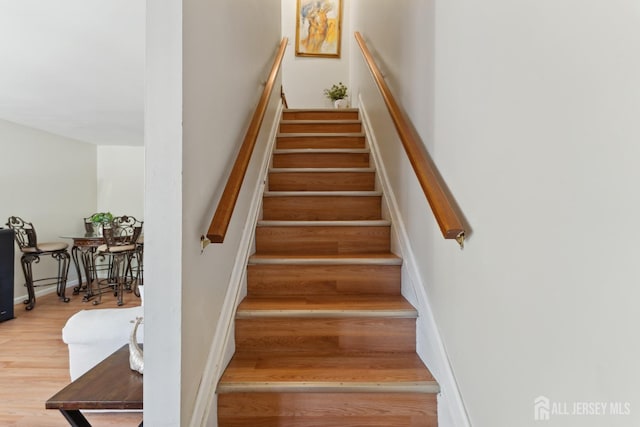 stairway with baseboards and wood finished floors
