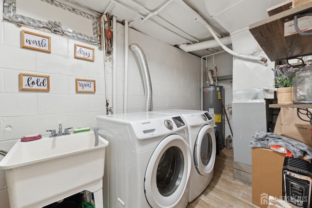 laundry room featuring a sink, laundry area, water heater, washer and clothes dryer, and light wood-style floors