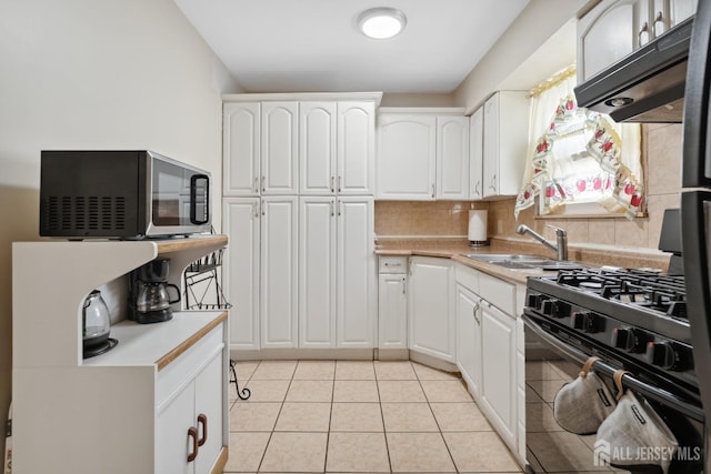 kitchen featuring stainless steel microwave, black range with gas cooktop, under cabinet range hood, light countertops, and tasteful backsplash