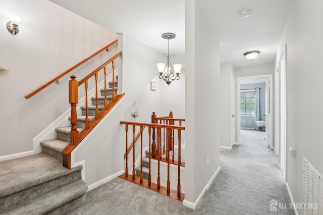 stairs featuring carpet, baseboards, and a chandelier