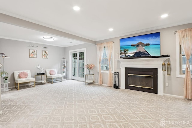 carpeted living area featuring a glass covered fireplace, crown molding, baseboards, and recessed lighting