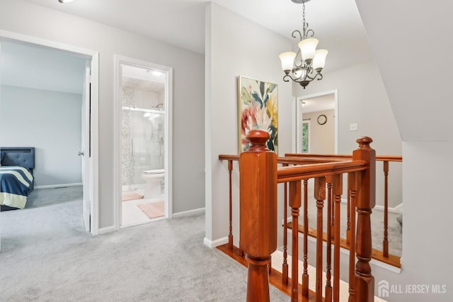 hallway with an upstairs landing, a chandelier, carpet, and baseboards
