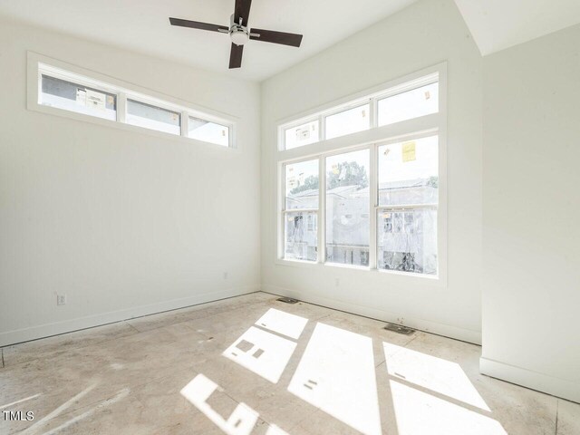 empty room with ceiling fan and a wealth of natural light