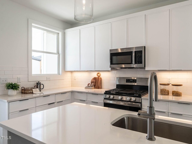 kitchen featuring a sink, backsplash, white cabinetry, appliances with stainless steel finishes, and light countertops